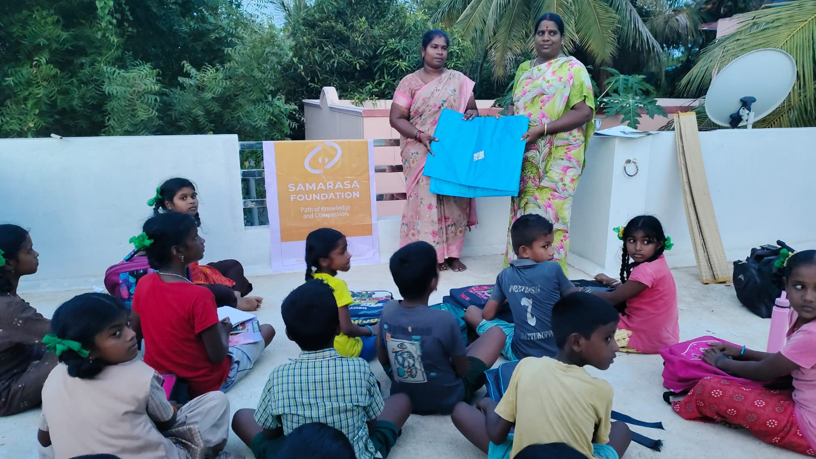 An outdoor session with children seated around two facilitators.